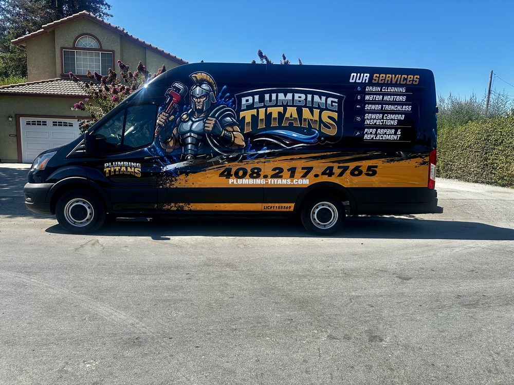 The Plumbing Titans van parked outside a house, wrapped in black and gold with the Titan mascot, the phone number and the services list along the side